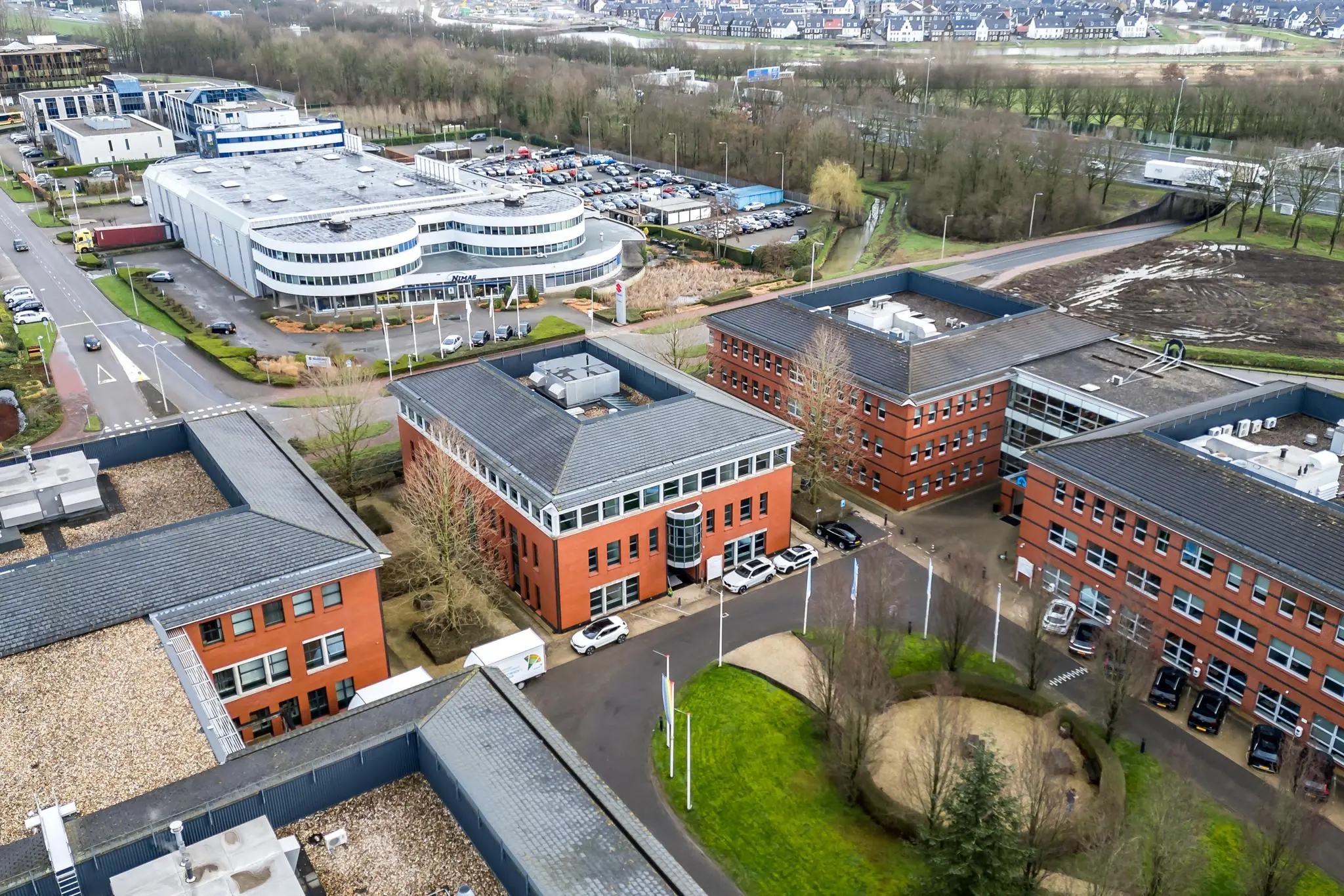 Luchtfoto van een kantoorgebied aan de Lange Dreef met meerdere rode bakstenen gebouwen en een modern wit pand.